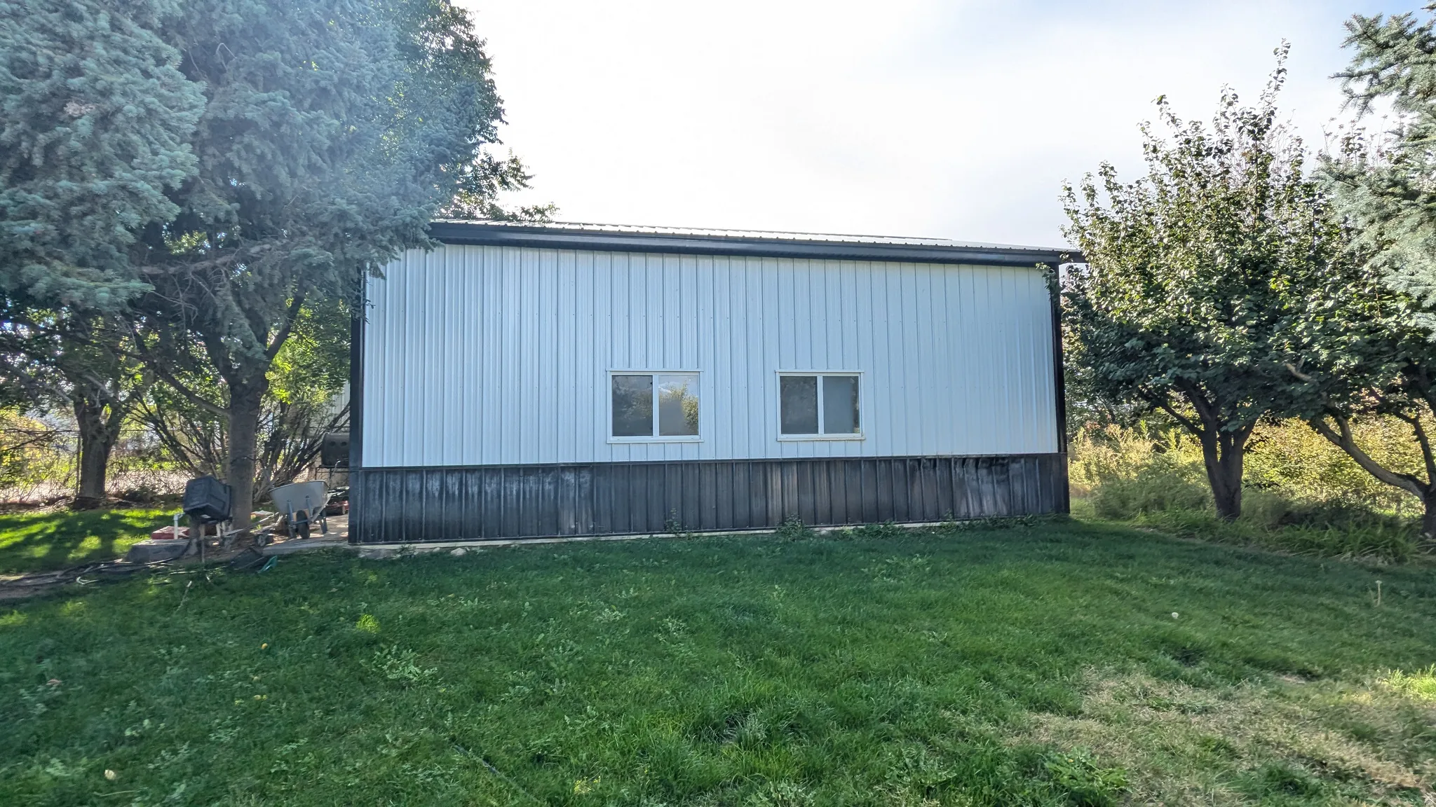Metal-sided accessory structure featuring a dark base and two windows