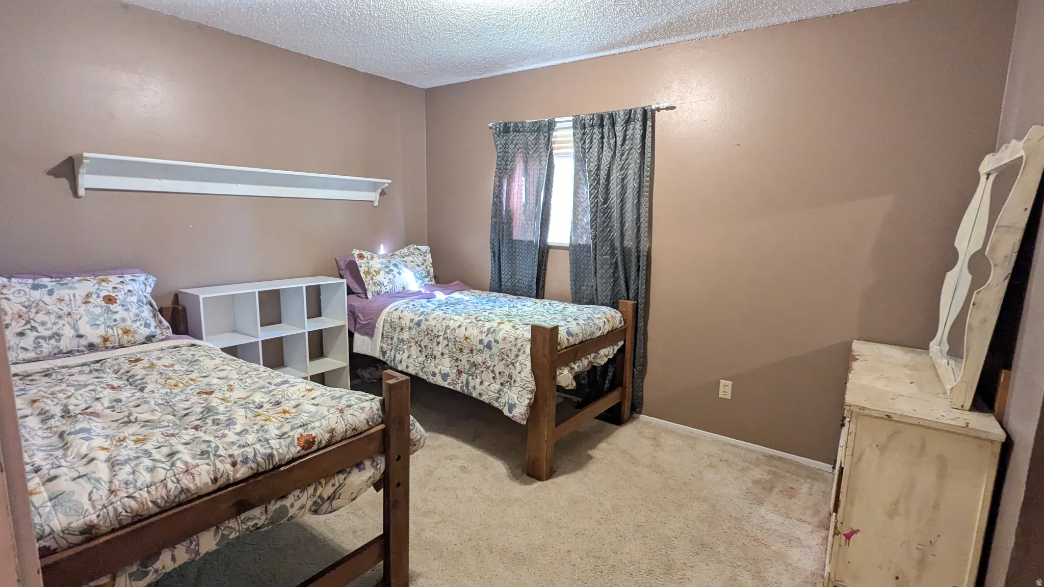 Wall-to-wall carpeting, window with privacy coverings, and a wall-mounted shelving unit