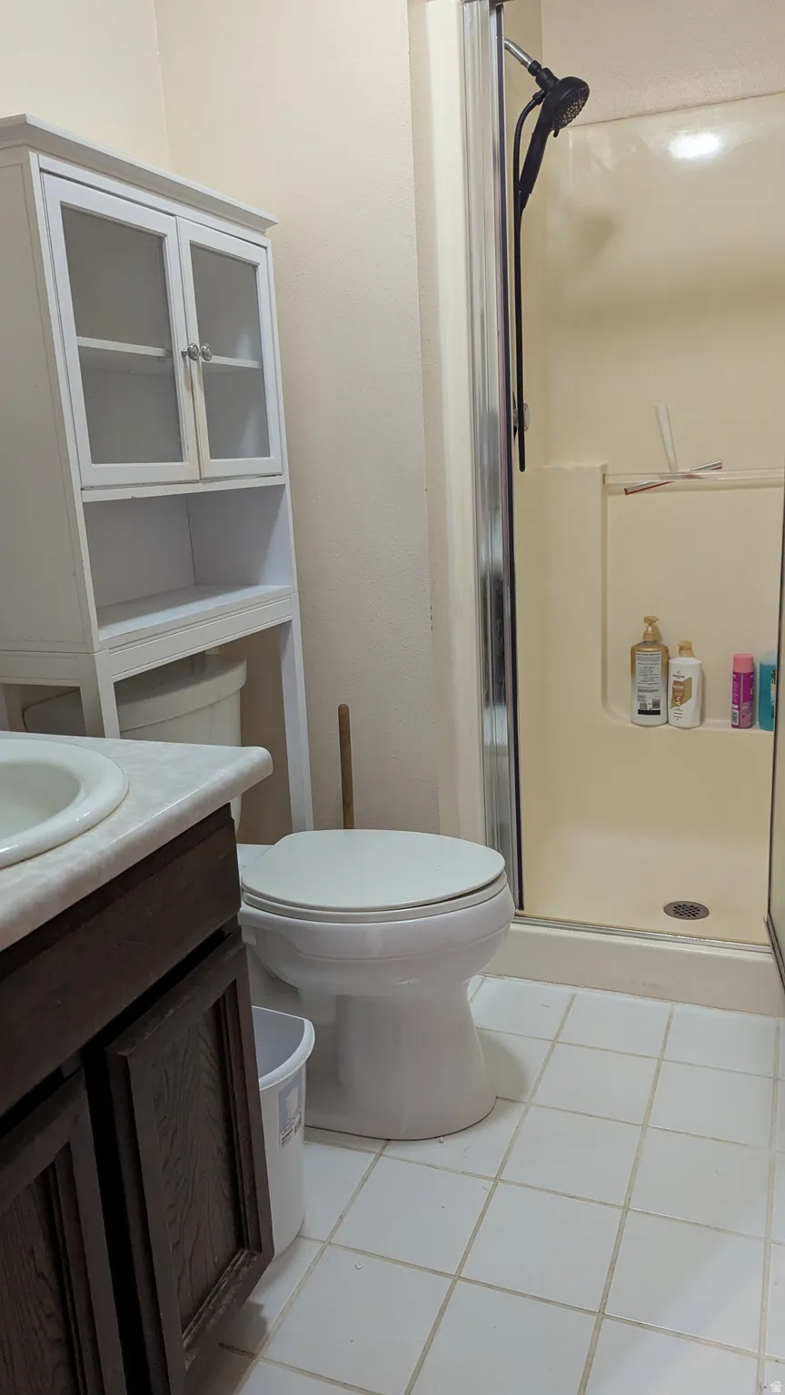 White tiled flooring, vanity with dark wood-finish cabinetry, and a white countertop with an integrated sink