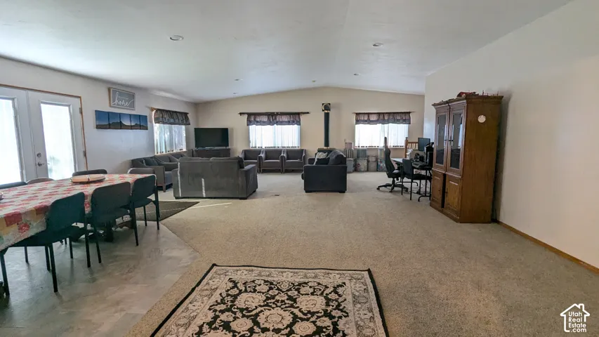 Spacious open-concept room featuring a wood-burning stove, multiple windows with blinds, a large dining area, and neutral wall paint