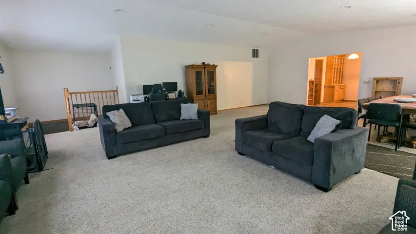 Spacious room with light-toned walls, recessed lighting, and a large carpeted area