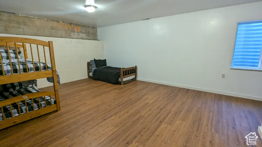 Wood-finish flooring with white painted walls and a window featuring horizontal blinds