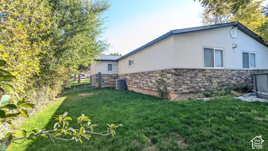 Stucco exterior with a stone veneer foundation, multiple sliding windows, and a manicured lawn