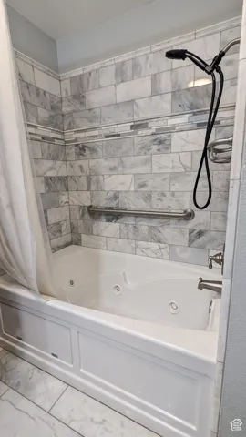 Soaking tub with integrated jets, subway tile surround, decorative mosaic tile accent, and brushed nickel fixtures