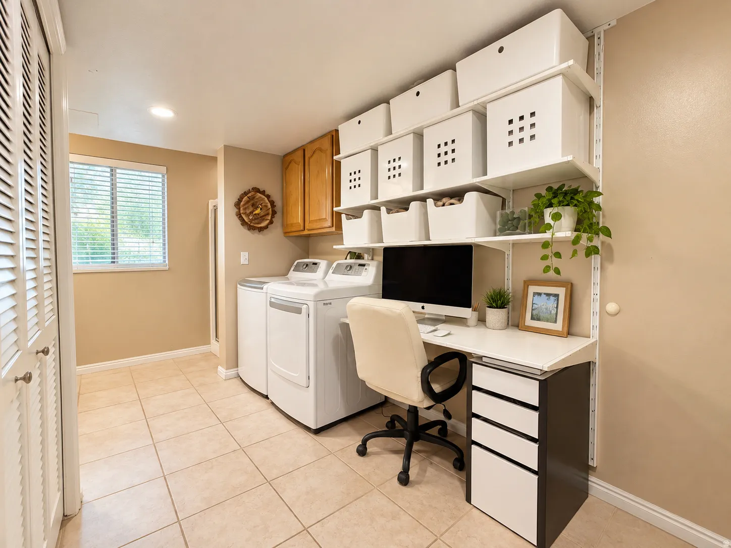 Integrated laundry appliances, built-in shelving, wood-finish cabinetry, tile flooring, and louvered bifold doors