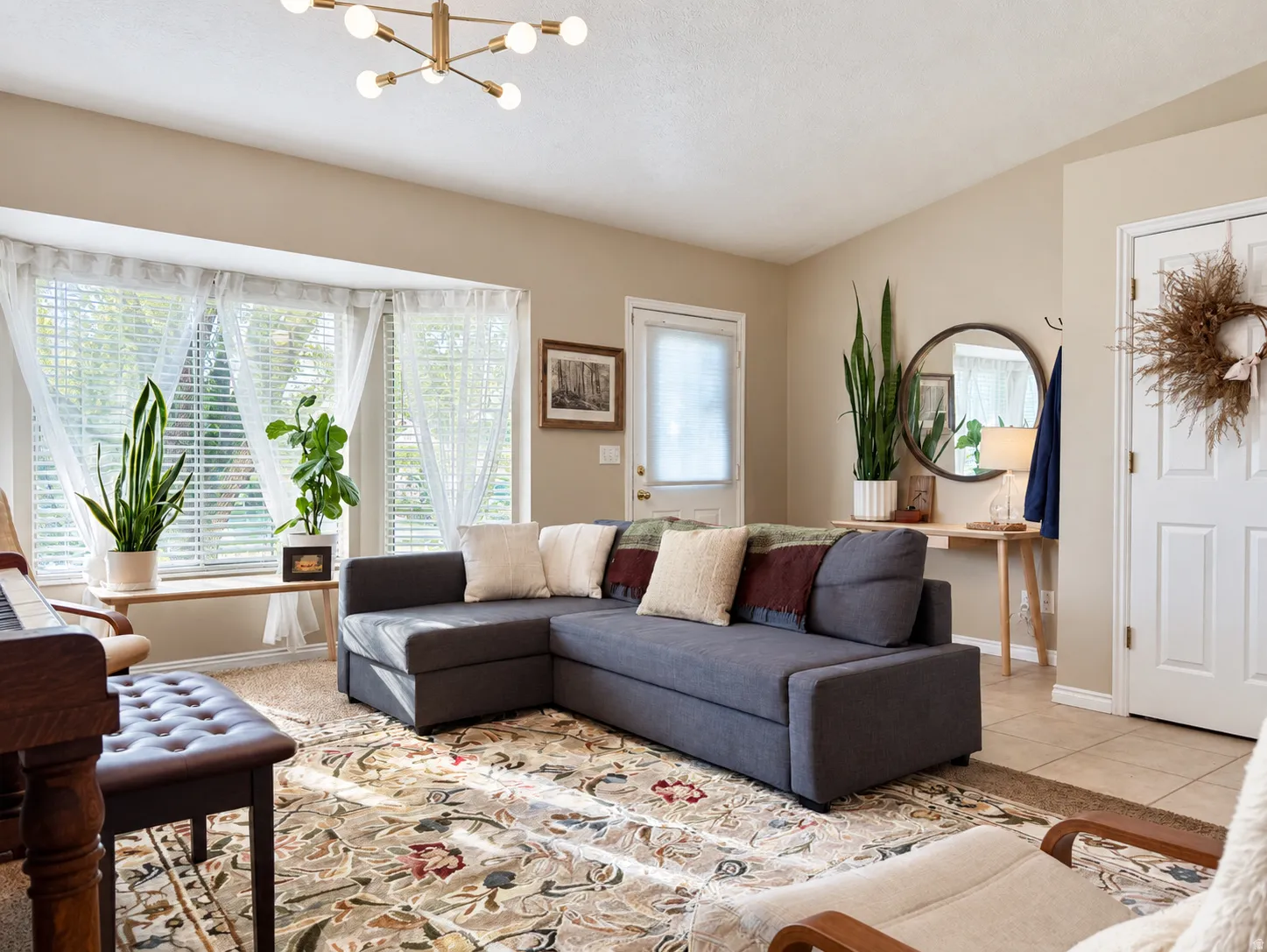Bay window, vaulted ceiling, modern sputnik chandelier, light neutral wall color, and tile flooring at entry