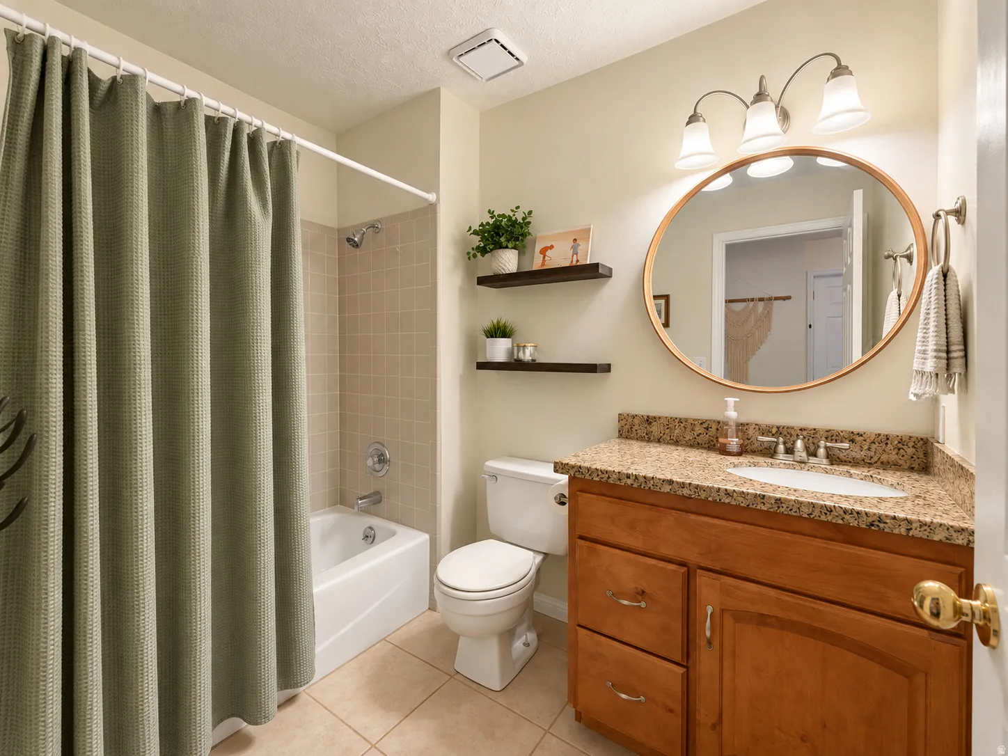 Bathroom featuring a tile floor, wood-finish vanity with a granite-style countertop, oval mirror, and three-light vanity fixture