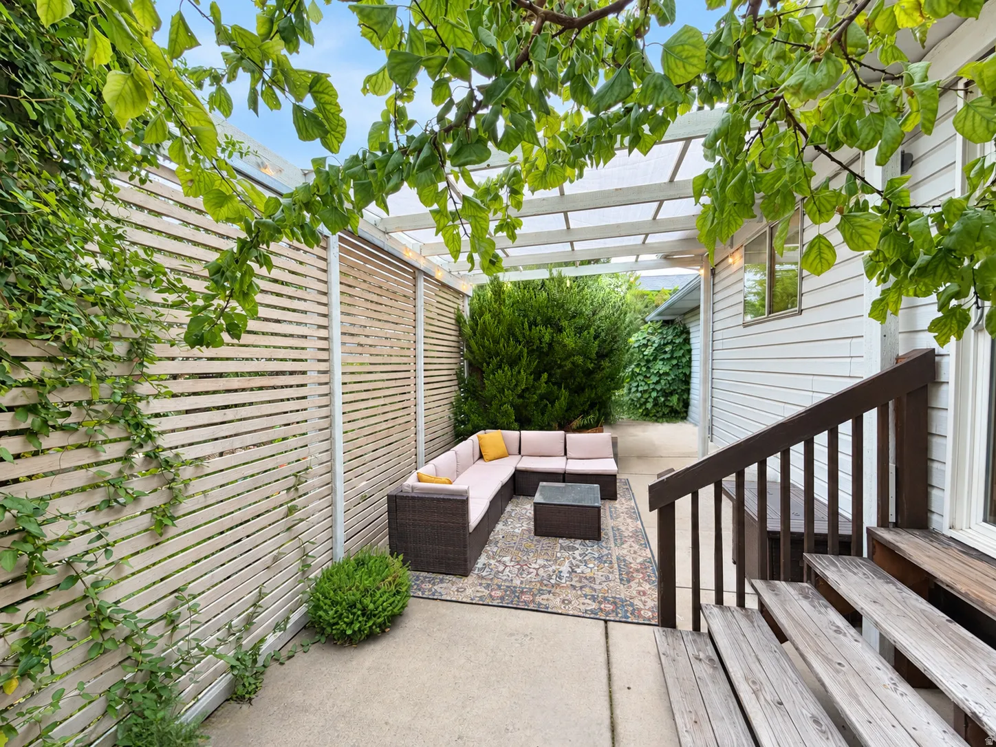 Private concrete patio with a slatted privacy fence and a white pergola
