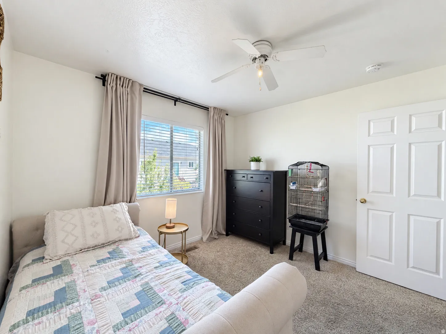Carpeted flooring, a window with blinds, and a white ceiling fan with integrated lighting