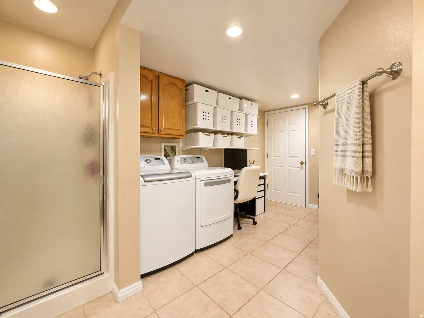 Frosted glass shower enclosure, wood-finish cabinetry, recessed lighting, and tile flooring