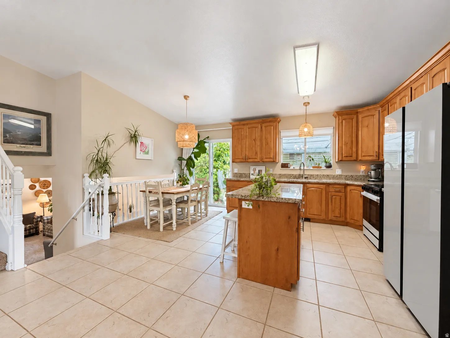 Kitchen featuring a central island with a granite countertop, wood cabinetry, tile flooring, and a glass slider