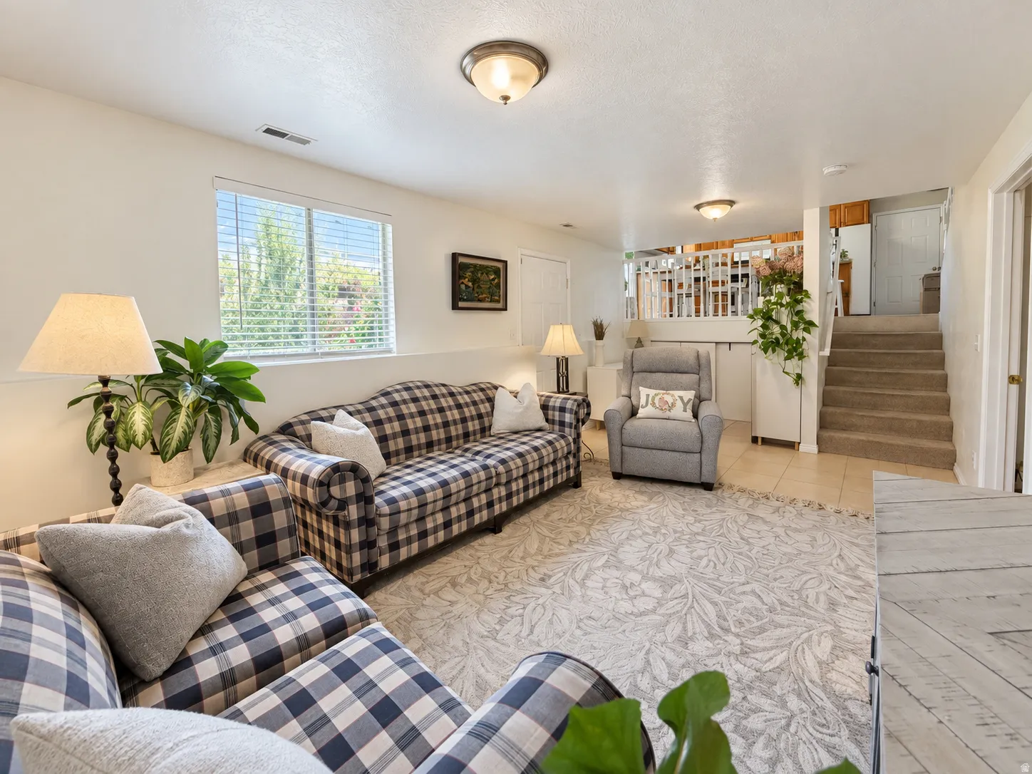 Recessed window with blinds, overhead lighting, tiled flooring, carpeted stairs, and a white balustrade