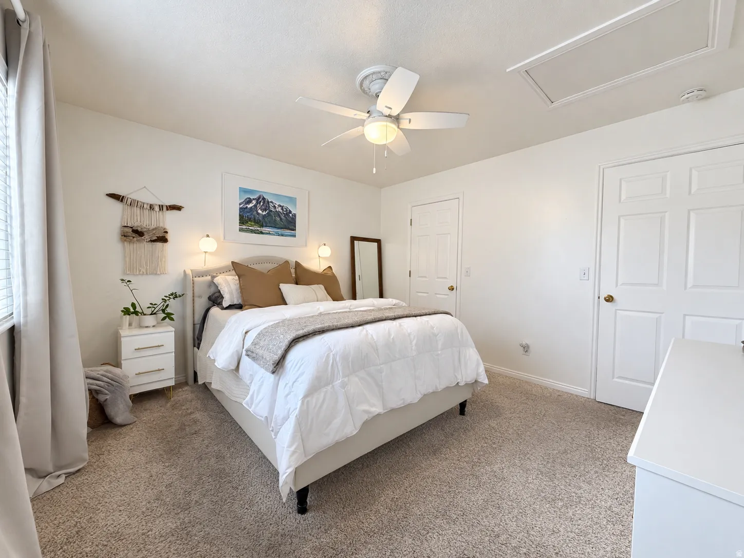Ceiling fan with integrated lighting, wall-mounted sconces, textured carpeting, and white interior doors