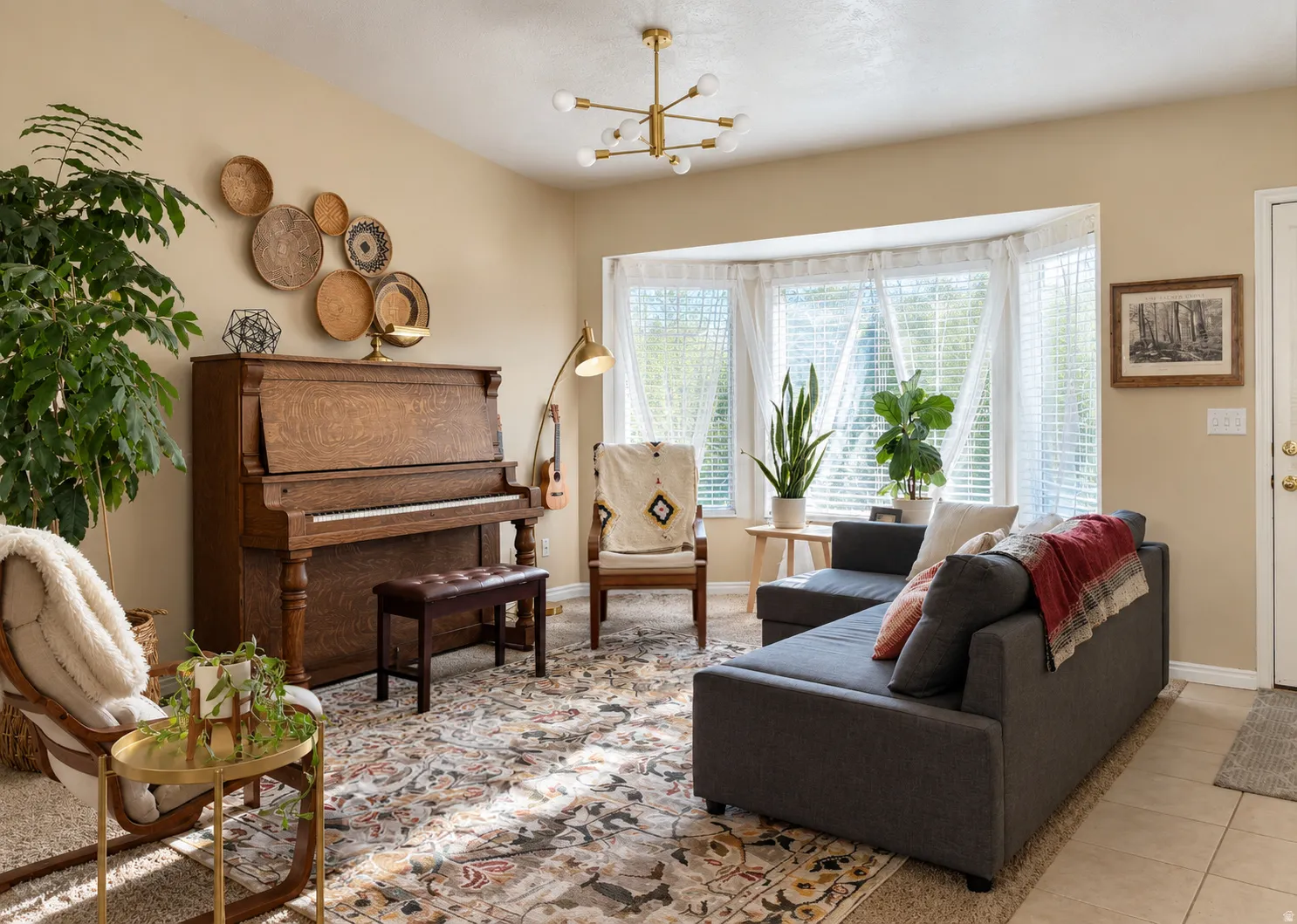 Spacious room featuring a bay window, a modern chandelier, light-toned wall paint, and tile flooring at the entrance