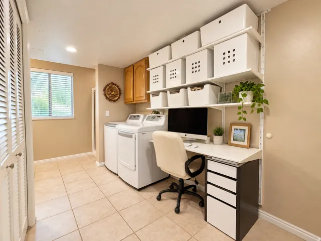 Integrated laundry appliances, built-in shelving, wood-finish cabinetry, tile flooring, and louvered bifold doors