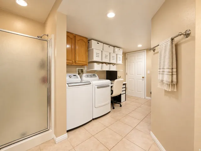 Frosted glass shower enclosure, wood-finish cabinetry, recessed lighting, and tile flooring