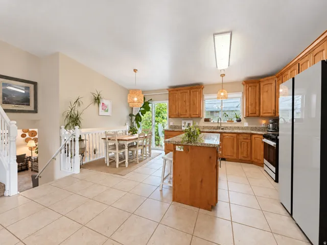 Kitchen featuring a central island with a granite countertop, wood cabinetry, tile flooring, and a glass slider