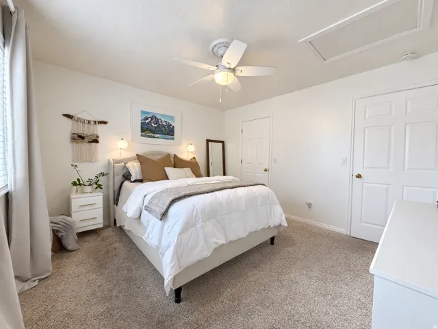 Ceiling fan with integrated lighting, wall-mounted sconces, textured carpeting, and white interior doors