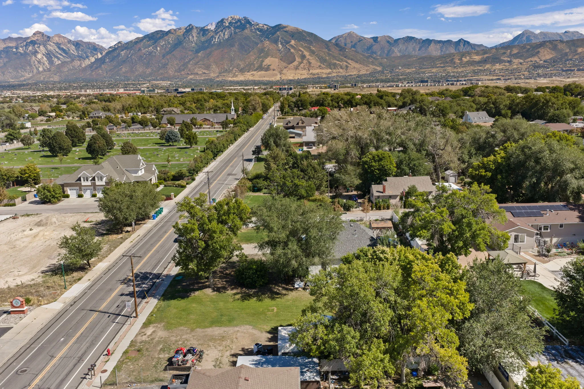 Mountain backdrop, residential area, mature trees, paved roads, clear sky