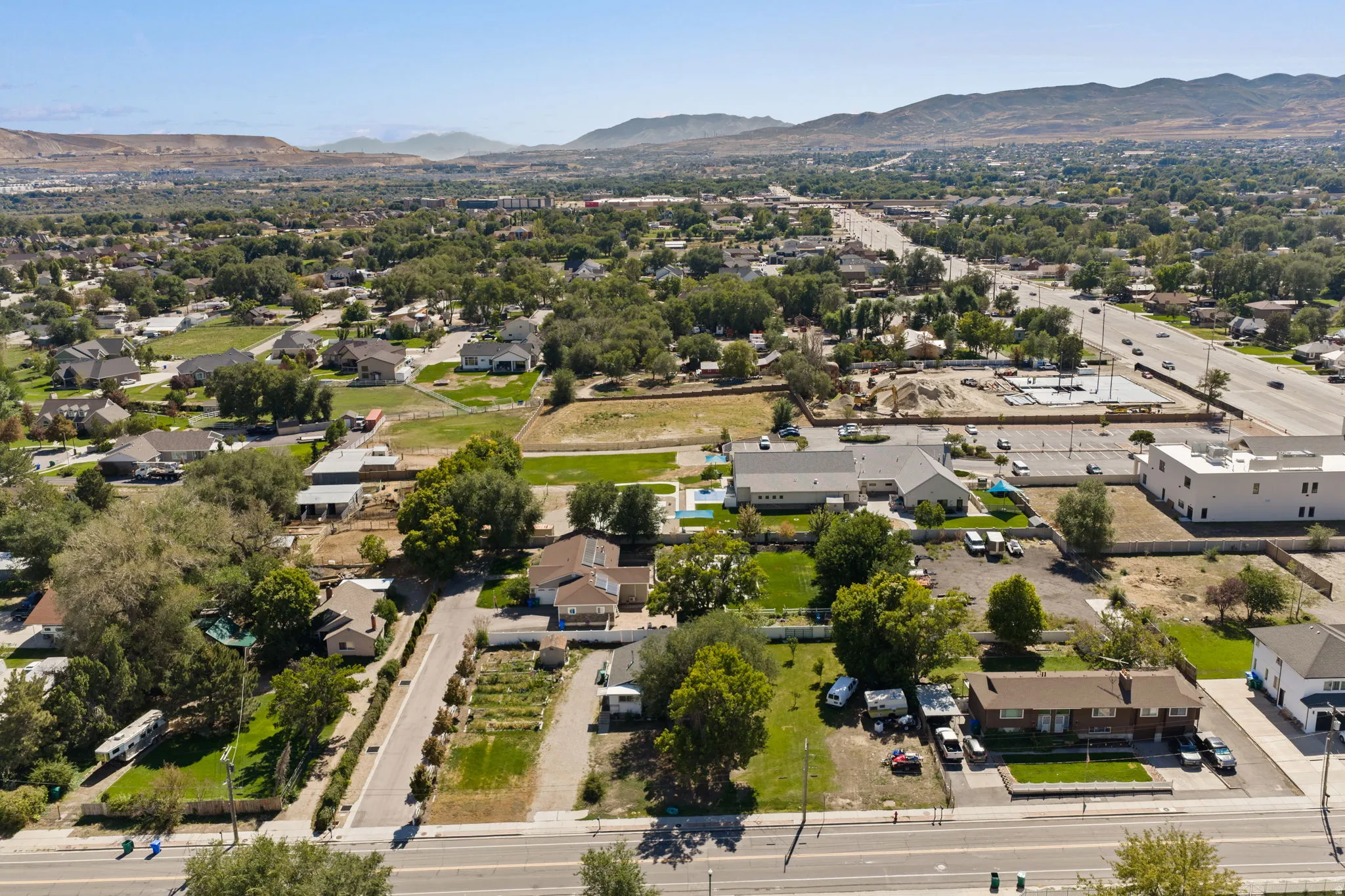 Aerial view showcasing this property's expansive grounds with mature landscaping, manicured lawn areas, and direct street frontage