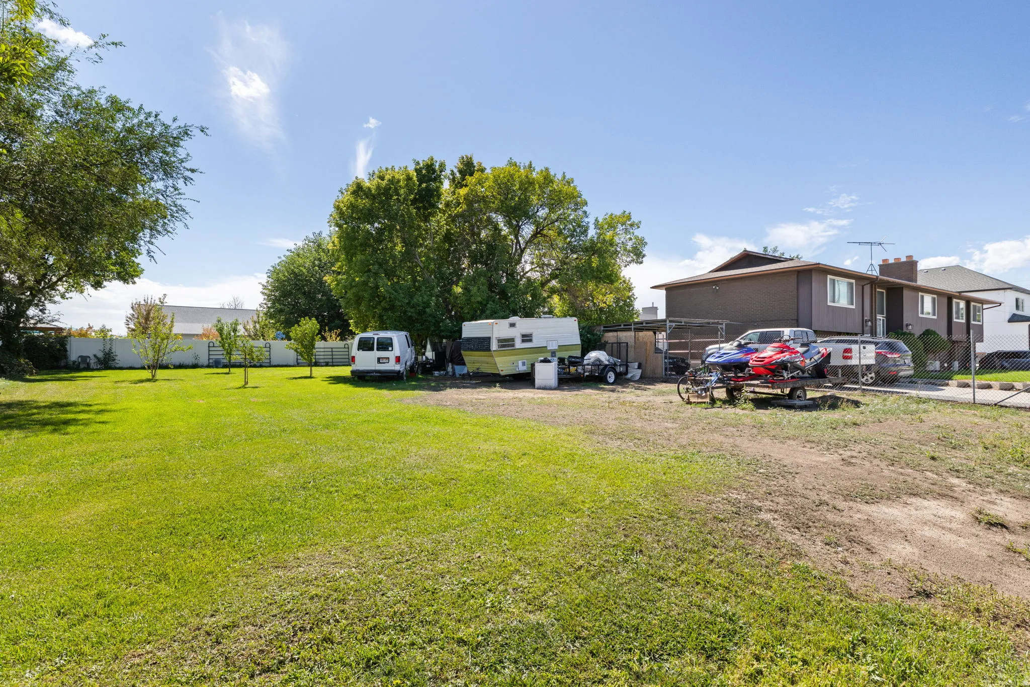 Expansive lot featuring mature trees, a manicured lawn, and a partial privacy fence