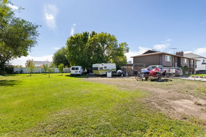 Expansive lot featuring mature trees, a manicured lawn, and a partial privacy fence