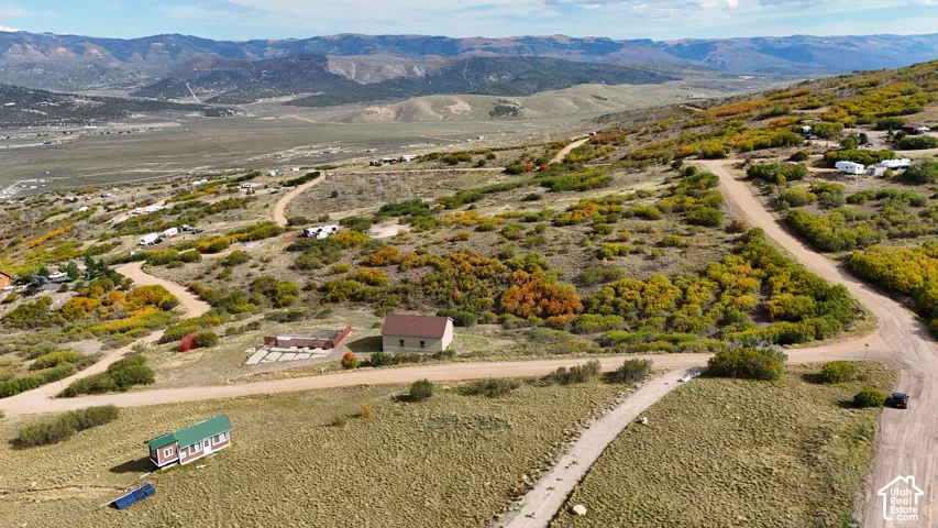 Aerial perspective of expansive lot featuring mountain topography, native brush, and direct gravel road access