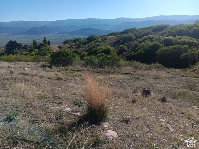 Expansive lot featuring a sloped terrain, natural vegetation, and distant mountain ranges