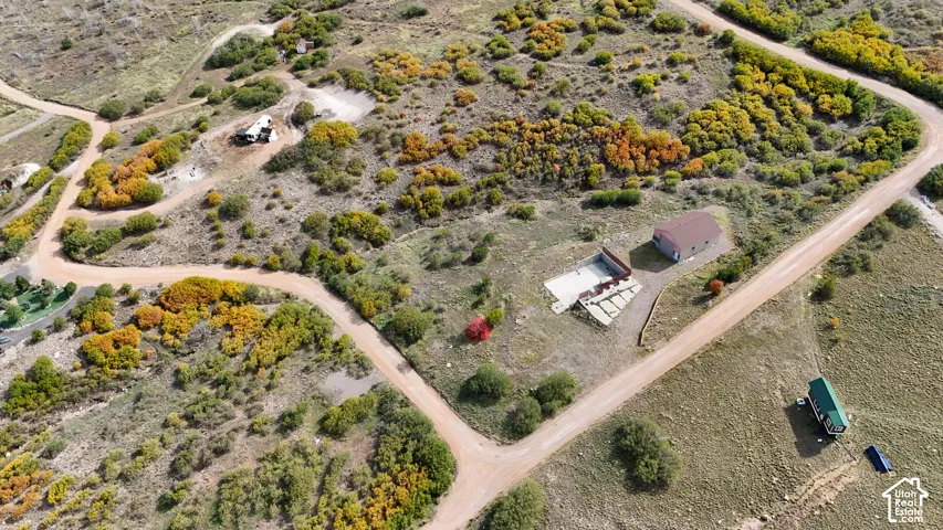 Elevated acreage featuring expansive natural terrain, native vegetation, established dirt access roads, and a concrete building foundation