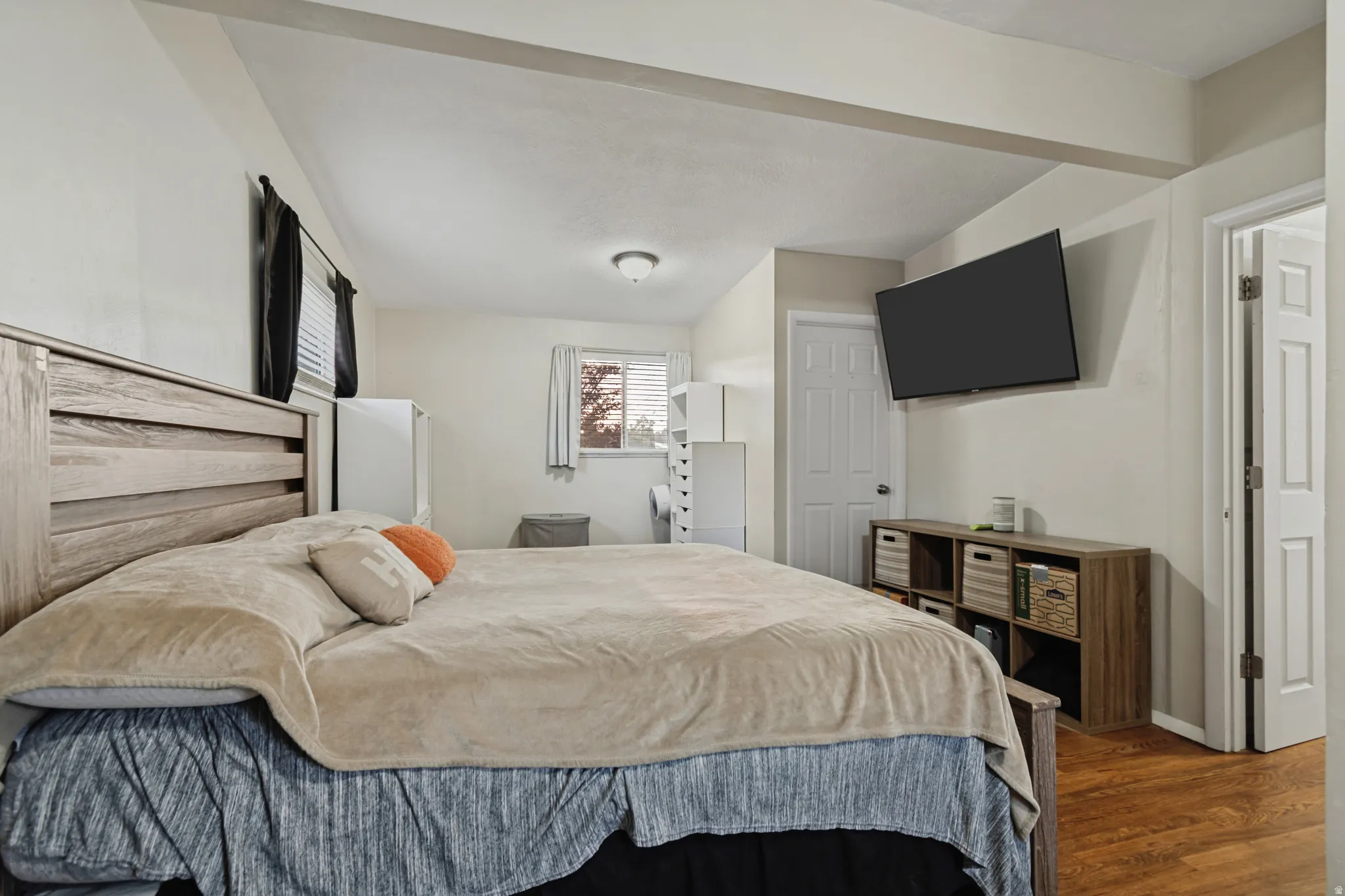 Recessed ceiling with exposed beams, light tone wall finish, wood-finish flooring, white paneled door