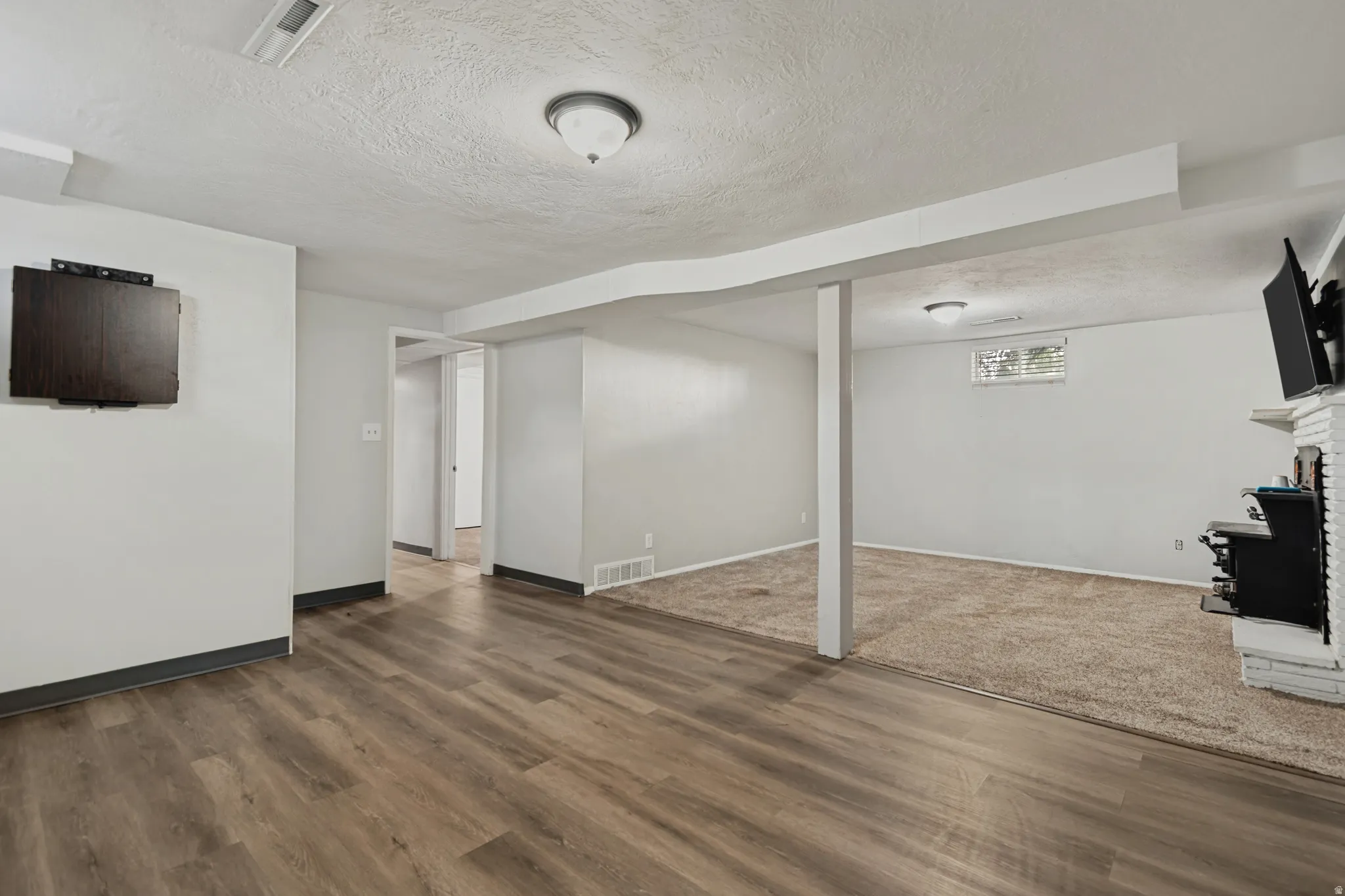 Spacious room featuring wood-finish flooring, recessed lighting, and a white brick fireplace
