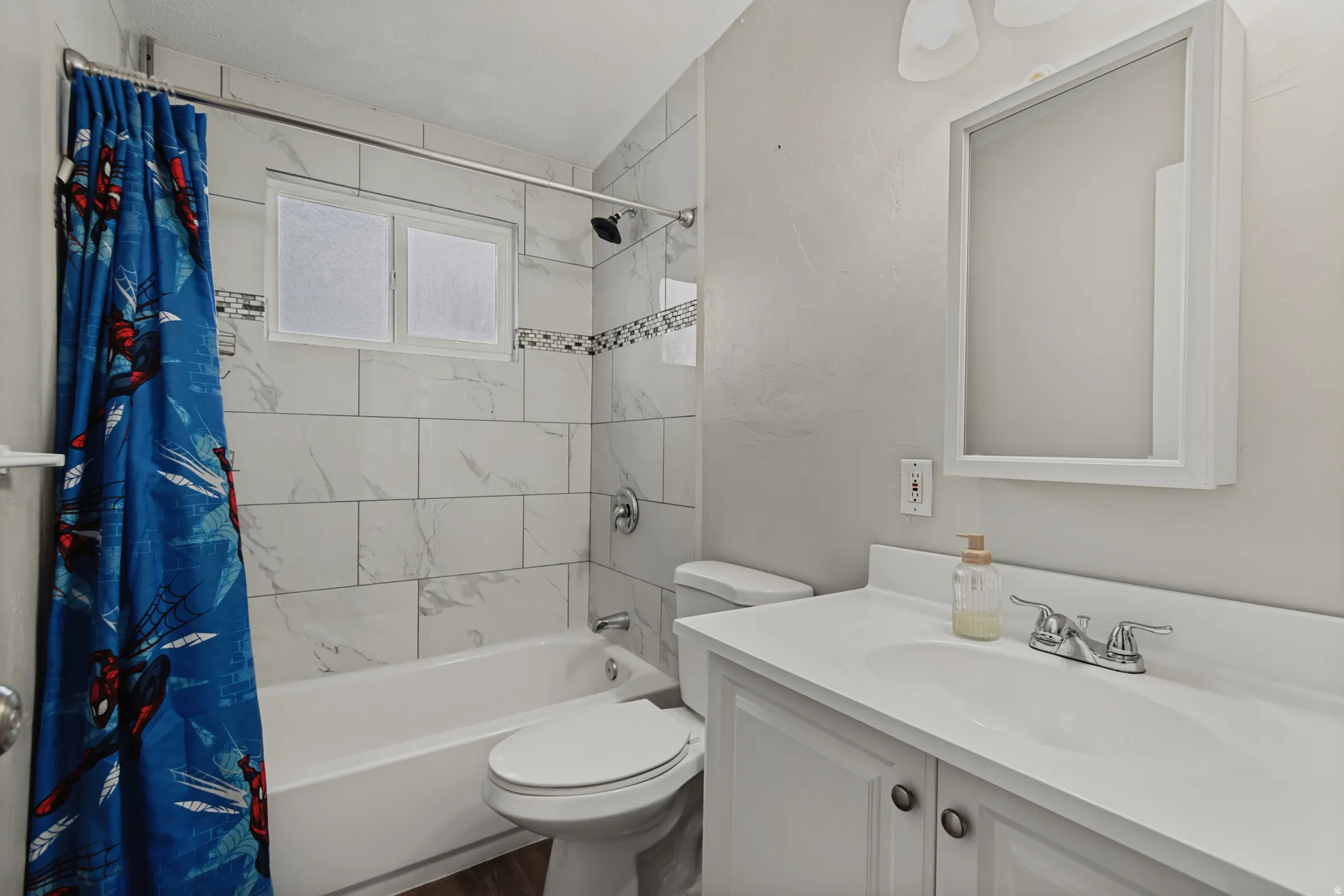 Bathtub with white subway tile surround, decorative accent tile, and a window