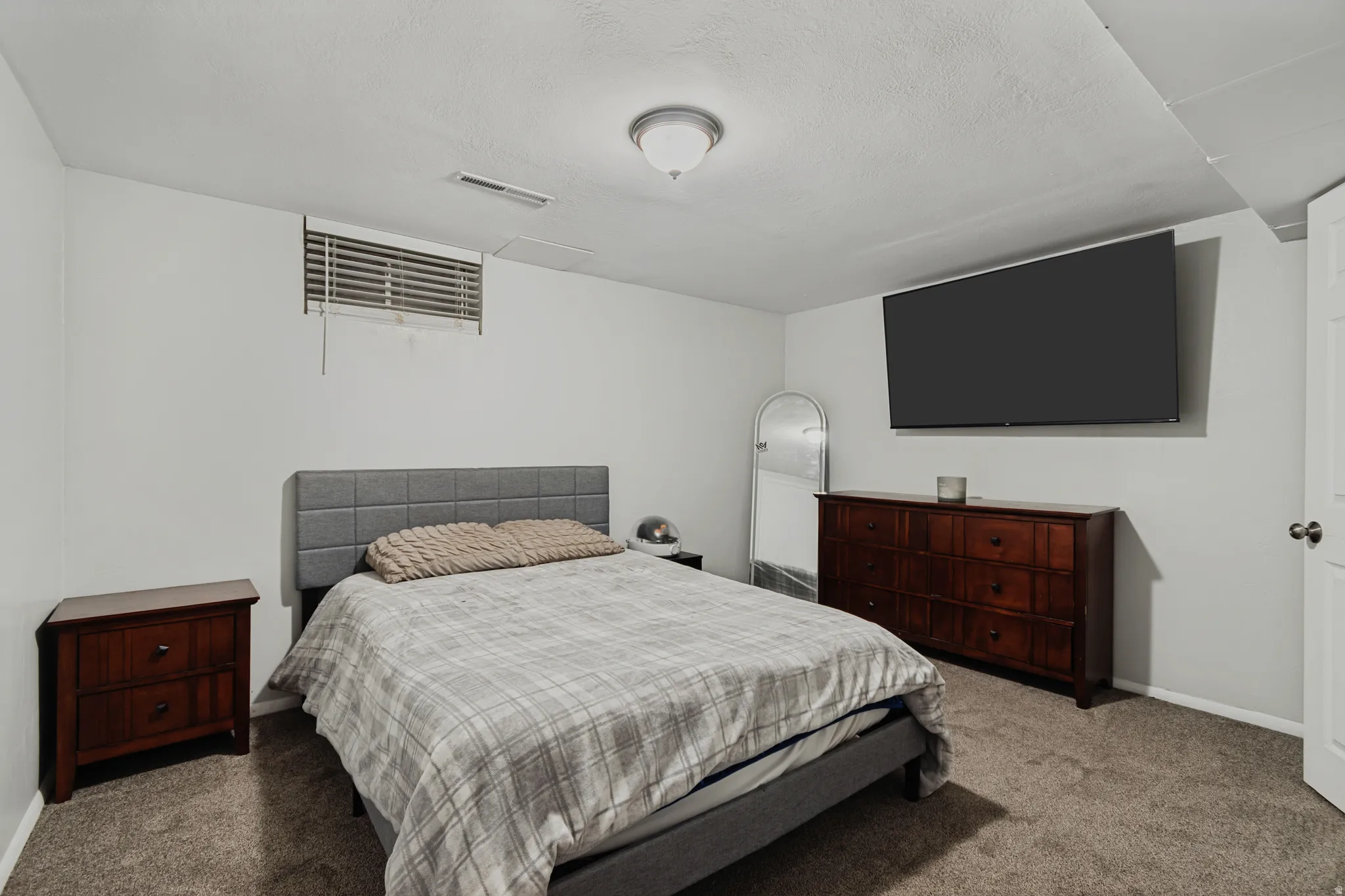 Carpeted room with a ceiling-mounted light fixture and a window with horizontal blinds