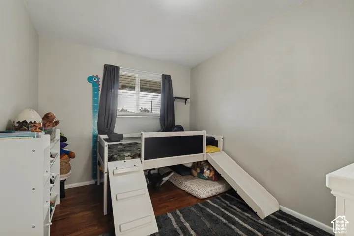 Wood-finish flooring, neutral wall color, and a window with blinds