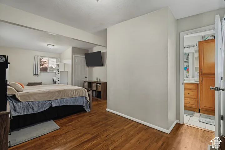 Wood-finish flooring throughout, ceiling-mounted light fixtures, built-in shelving, and an adjacent bathroom with wood cabinetry