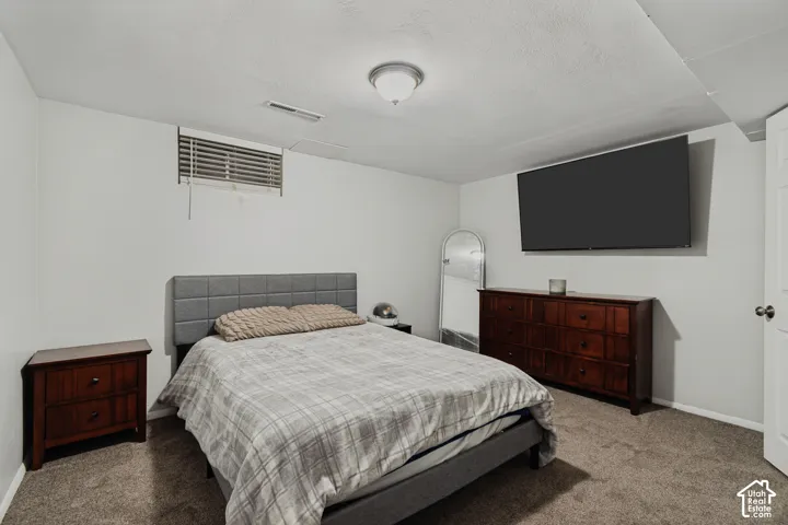 Carpeted room with a ceiling-mounted light fixture and a window with horizontal blinds