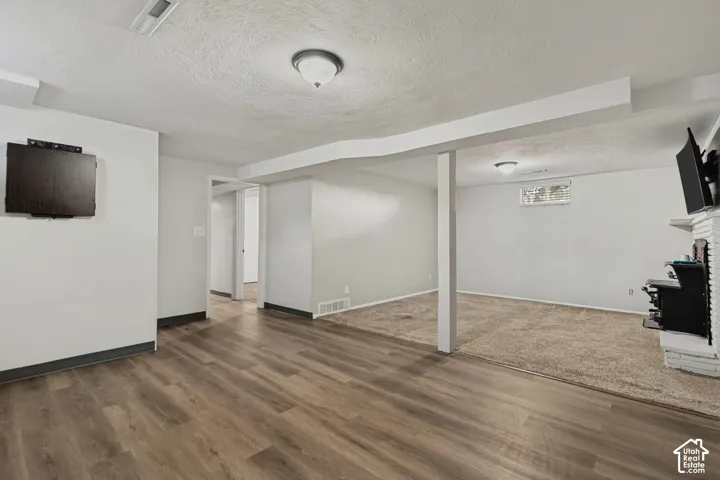 Spacious room featuring wood-finish flooring, recessed lighting, and a white brick fireplace