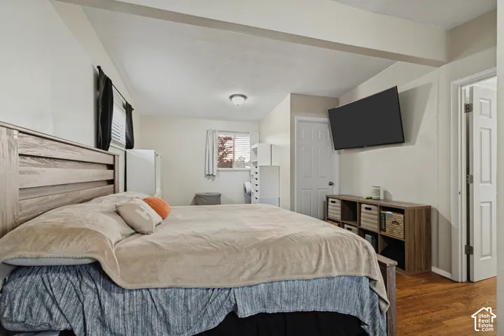 Recessed ceiling with exposed beams, light tone wall finish, wood-finish flooring, white paneled door