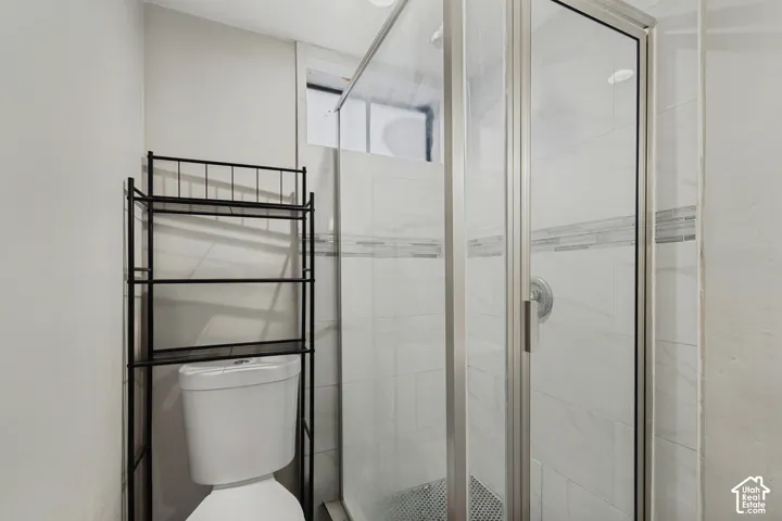 Glass-enclosed shower with a tiled surround, accent tile band, and polished chrome fixtures