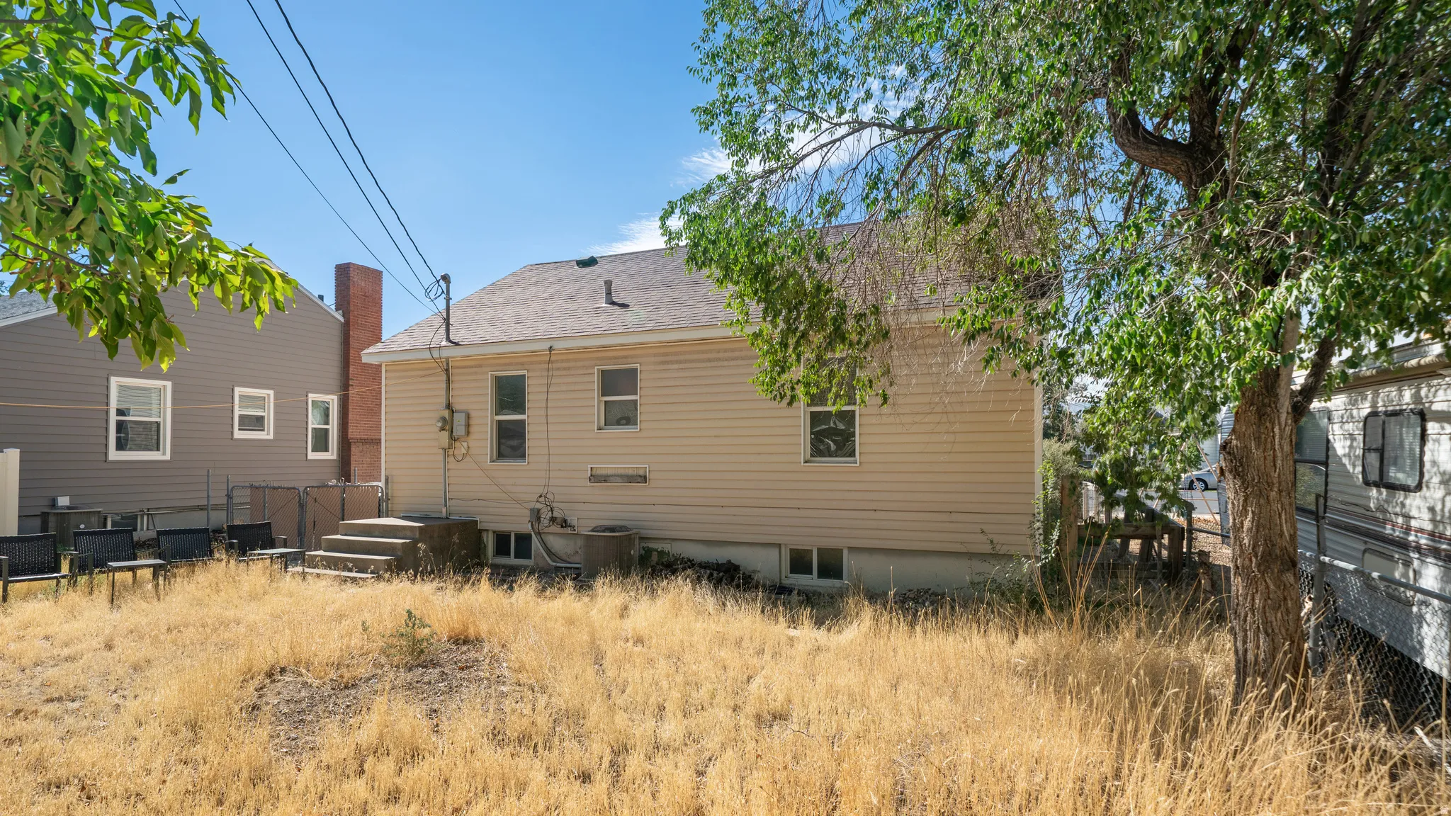 Beige siding exterior with a concrete staircase leading to a rear entry