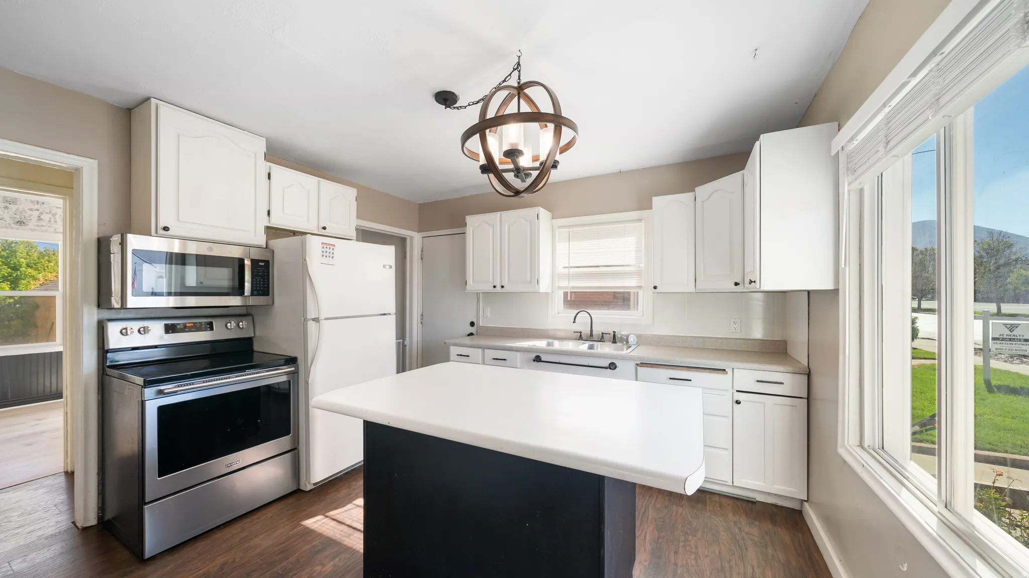 Kitchen featuring white cabinetry, a central island with a white countertop, stainless steel appliances, and wood-finish flooring