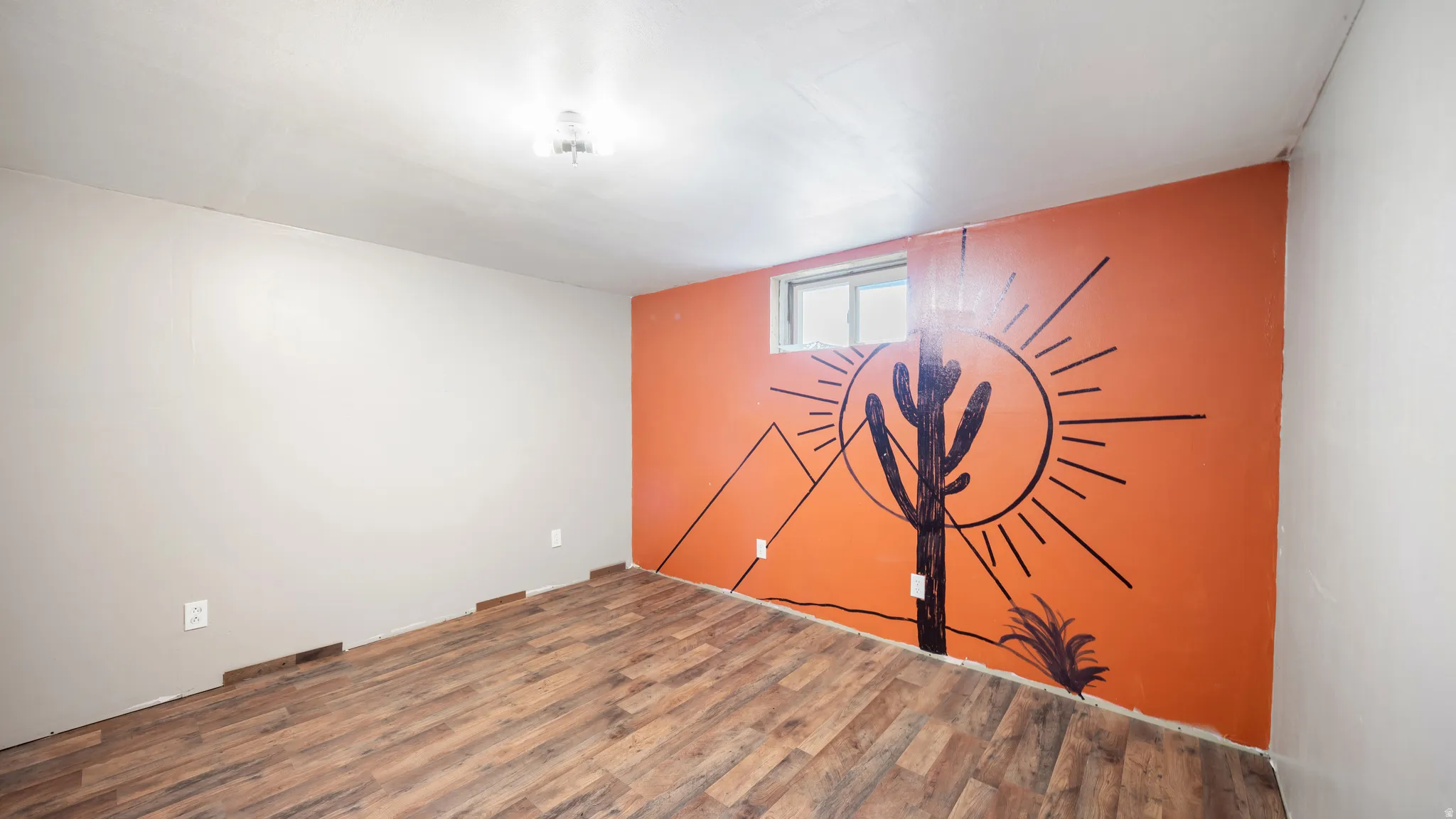 Wood-finish flooring, accent wall with graphic mural, and a single-pane window