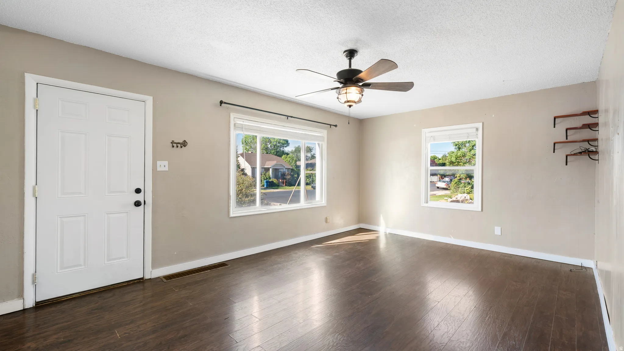 Wood-finish flooring, white painted walls, and a ceiling fan with integrated lighting