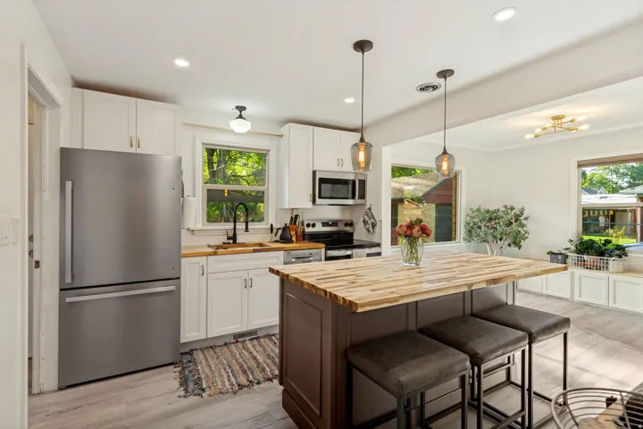 Kitchen featuring white cabinetry, stainless steel appliances, wood-finish countertops, and a central island with integrated seating