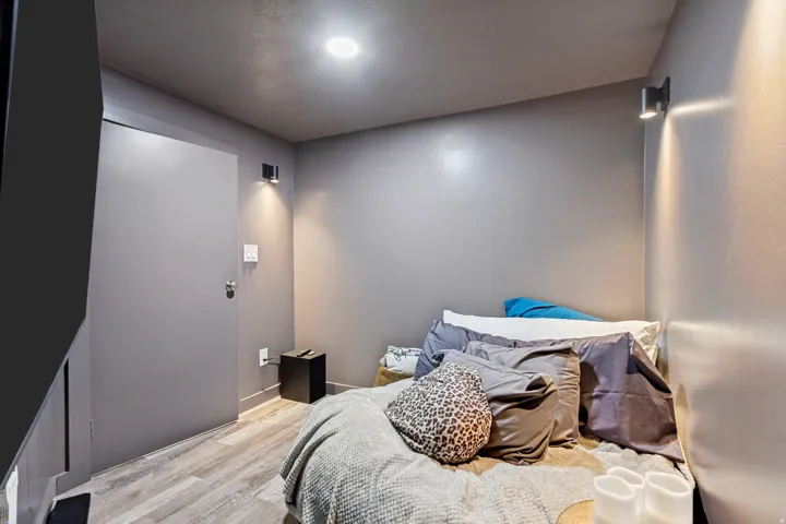 Recessed ceiling lighting, wood-finish flooring, two wall-mounted accent lights, and a solid door