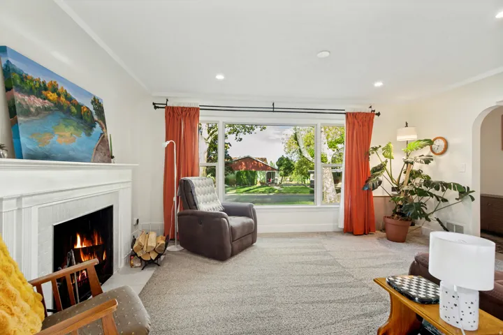 White mantel fireplace, large picture window, recessed lighting, and archway detail
