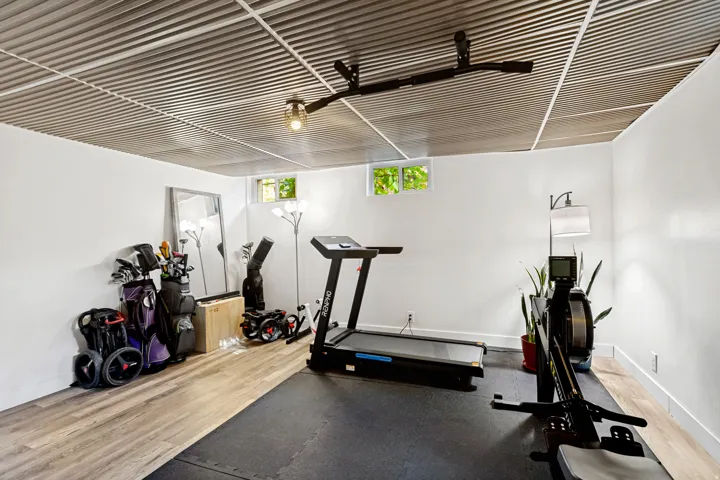 Corrugated metal ceiling with recessed lighting, light wood-finish flooring, white walls, and a window providing natural light