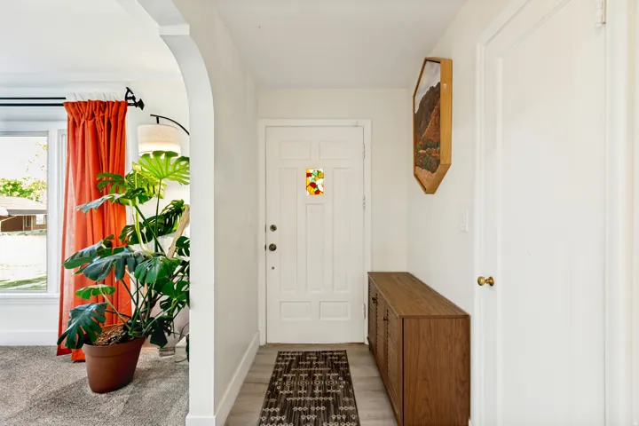 Entryway featuring wood-finish flooring, white paneled door, and a built-in wooden cabinet