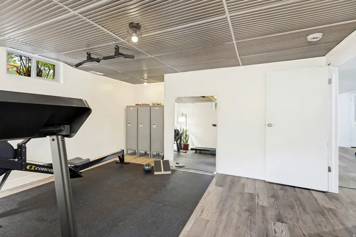 Corrugated metal ceiling, recessed window, light wood-finish flooring, white paneled doors, and wall-mounted light fixture