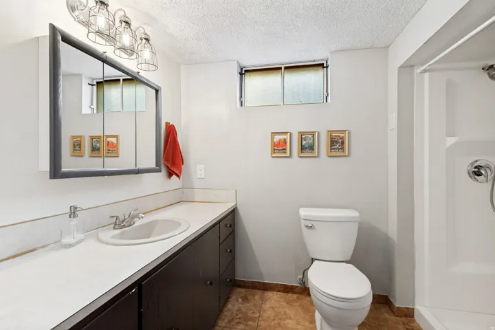 Built-in vanity with a white countertop and undermount sink, dark wood-finish cabinetry, and a mirrored medicine cabinet